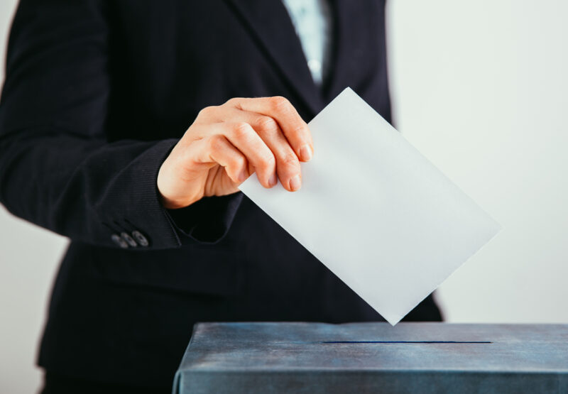 Close-up of voter putting ballot into voting box. Close-up of voter putting ballot into voting box.